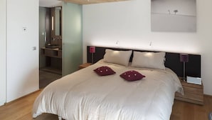 A bedroom with a large bed, two nightstands, a mirror, and a painting on the wall. - Mineral Lodge - Les Arcs Paradiski (villaroger)
