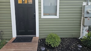 A house with a black front door, a small window, and a green siding exterior. - South Shore Studio in Mastic (Mastic)