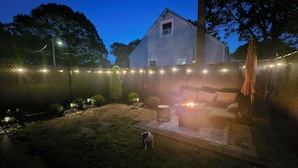 A backyard with a fire pit, outdoor furniture, and string lights. - South Shore Studio in Mastic (Mastic)