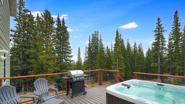 A wooden deck with a hot tub, grill, and Adirondack chairs. - Summit Lodge (Fairplay)