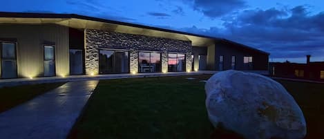 A modern building with a stone facade, large windows, and a well-lit entrance.
