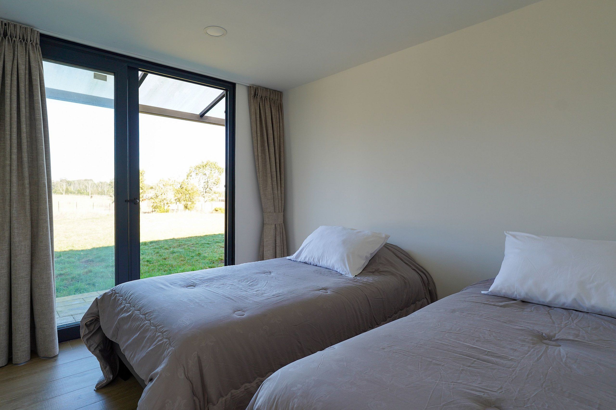 A bedroom with two beds, a large window, and a view of the outdoors.