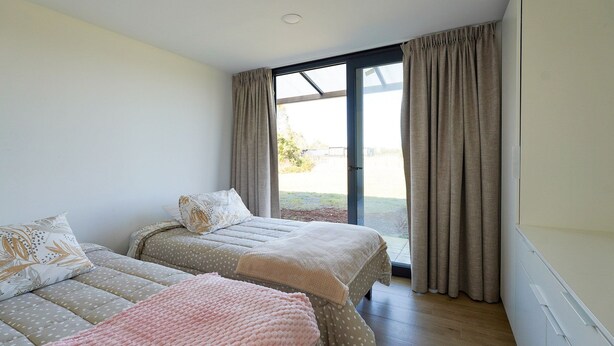 A bedroom with two beds, a large window, and a sliding glass door. - Oceana Suites Las Tranqueras (Puerto Varas)