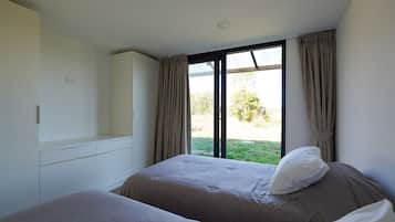 A bedroom with two beds, a wardrobe, and a large window with curtains.