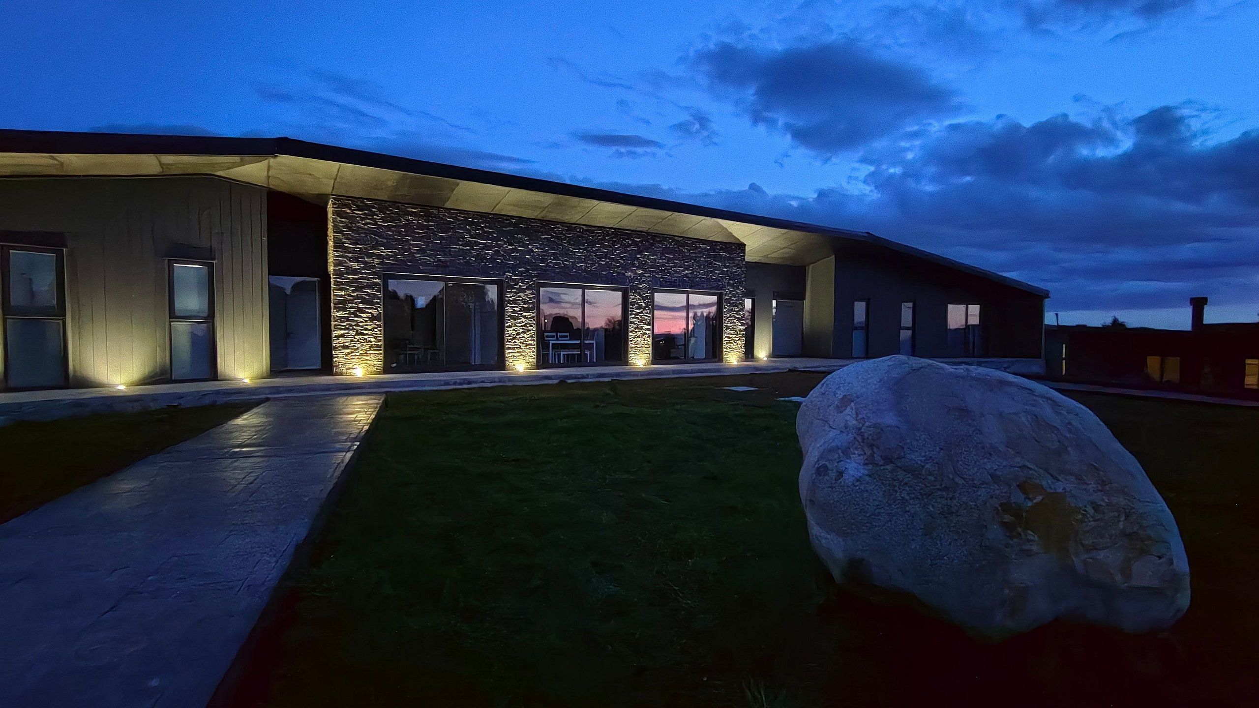 A modern building with a stone facade, large windows, and a well-lit entrance.