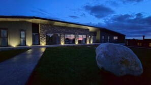 A modern building with a stone facade, large windows, and a well-lit entrance. - Oceana Suites Las Tranqueras (Puerto Varas)