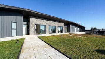 A modern building with a flat roof, large windows, and a paved walkway.
