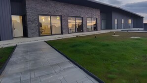 A modern building with large glass windows, a stone facade, and a paved walkway leading to the entrance. - Oceana Suites Las Tranqueras (Puerto Varas)
