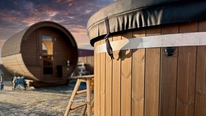 Un bâtiment en forme de tonneau, fait de bois, avec un banc et une table situés à proximité.