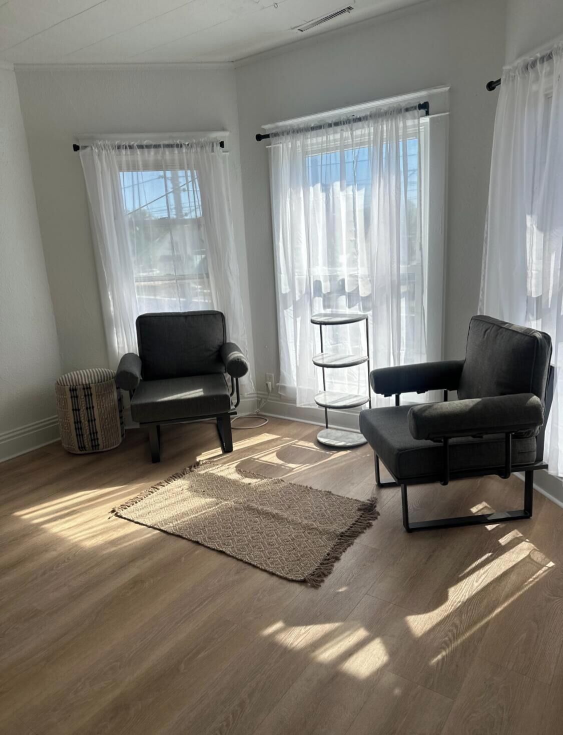 Une pièce spacieuse avec deux chaises noires, une petite table ronde et un panier en osier.