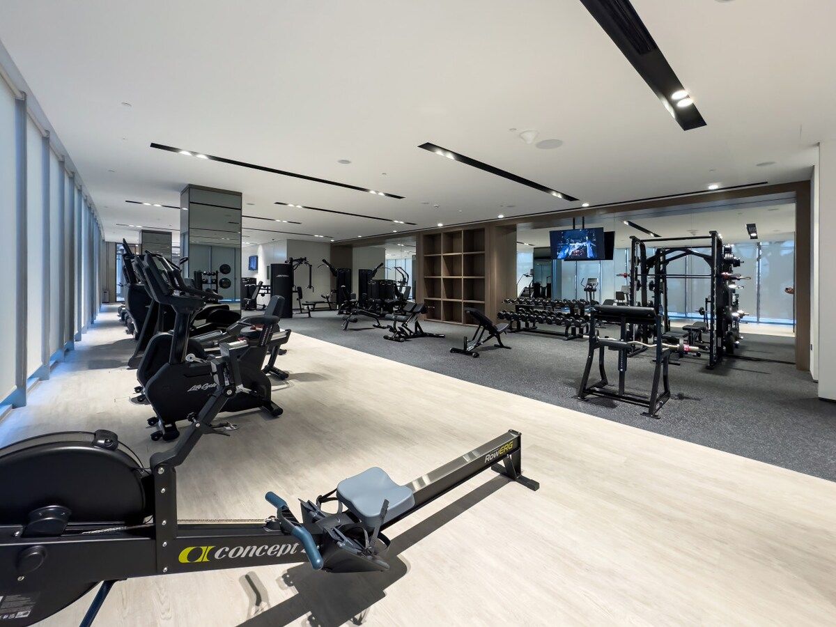 Et moderne fitnesscenter med løbebånd, træningsudstyr og spejle.