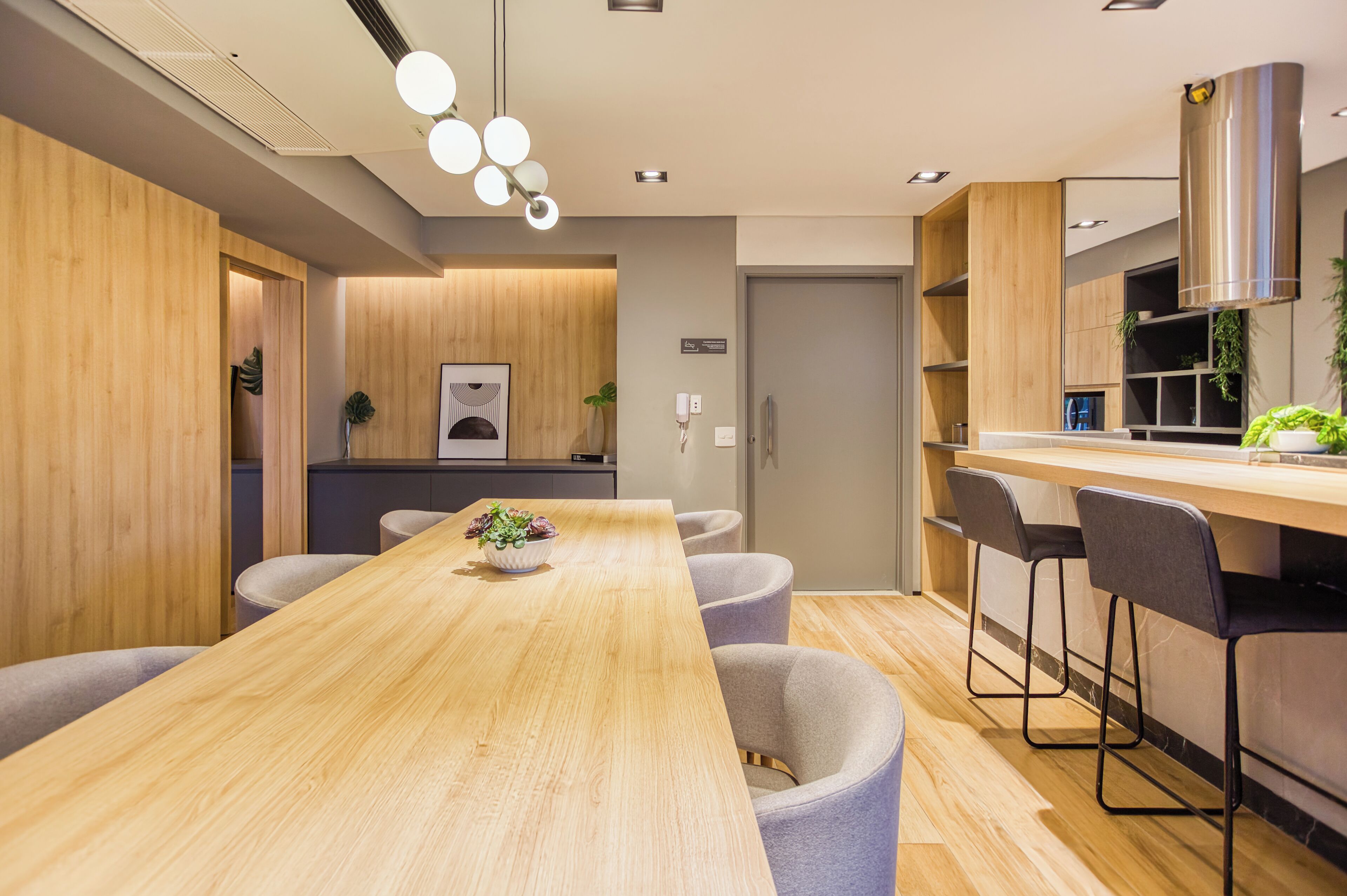 A modern kitchen with a wooden table, bar stools, and a built-in oven.