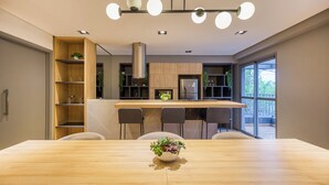 A modern kitchen with a central island, built-in shelves, and a dining area with a wooden table and chairs.