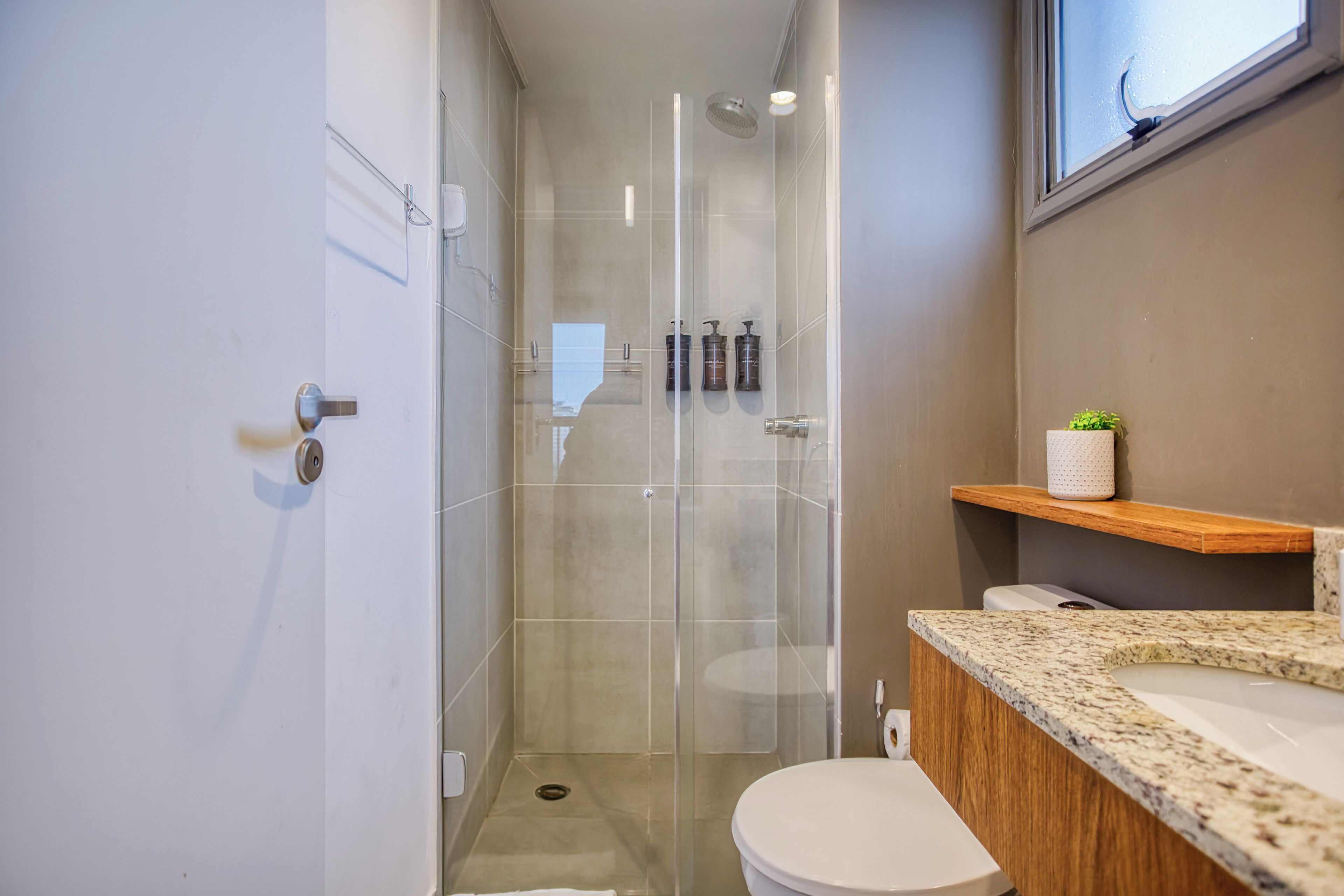Une salle de bain moderne avec une douche à parois de verre, des toilettes blanches et un comptoir en granit.