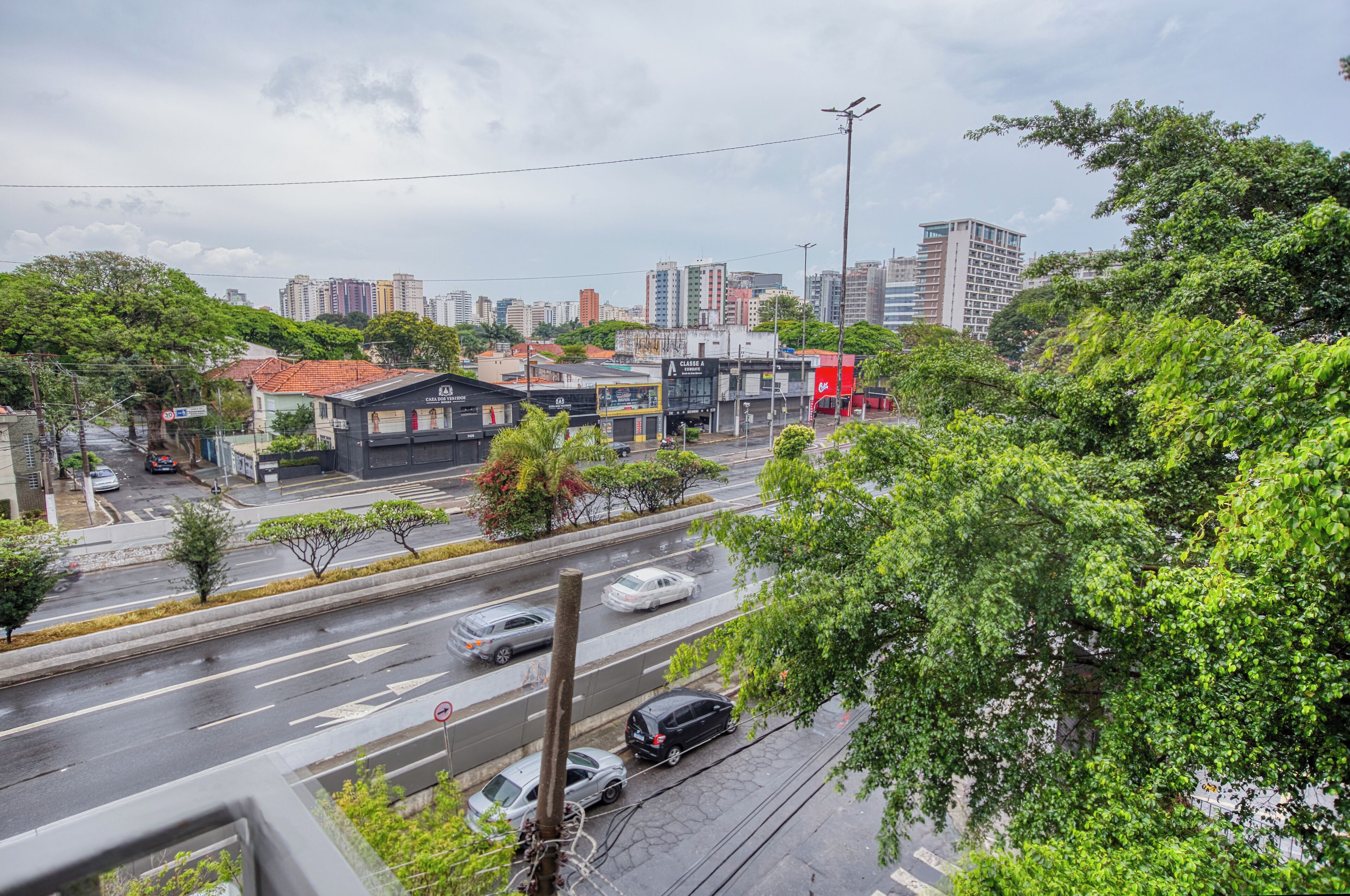A cityscape with a multi-lane road, buildings, and greenery.