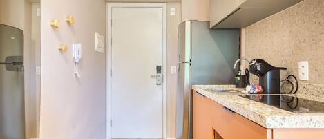 Una cocina compacta equipada con refrigerador, cafetera y microondas.