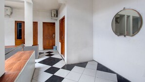 A hallway with a checkered floor, wooden doors, and a mirror on the wall. - Hotel O Near Tugu Yogyakarta 1 formerly Crown Residence (Yogyakarta)