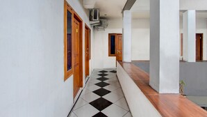 A hallway with a checkered floor, wooden doors, and a tiled wall. - Hotel O Near Tugu Yogyakarta 1 formerly Crown Residence (Yogyakarta)
