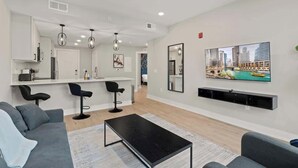 Una sala de estar moderna con un sofá, una mesa de centro y un televisor montado en la pared.