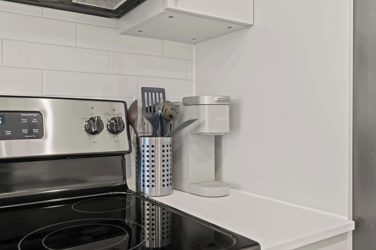 A kitchen with a stainless steel stove, a coffee maker, and a utensil holder on the countertop.