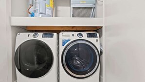 Dos lavadoras de carga frontal en un cuarto de lavado con un estante de madera arriba.