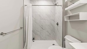 A modern bathroom with a shower, toilet, and built-in shelves. - Chic 1BR Luxury Apartment in Philly for 4 Guests (Philadelphia)