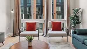 A modern living room with two sofas, a coffee table, and a potted plant. - Chic 1BR Luxury Apartment in Philly for 4 Guests (Philadelphia)