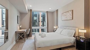 A modern hotel room with a large bed, a desk, and a chair. - Stylish 1BR Sleeps 4 near Independence Hall (Philadelphia)