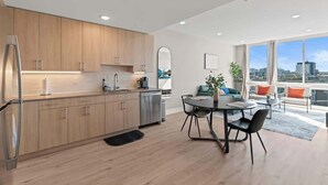 Een moderne keuken met houten kastjes, een roestvrijstalen koelkast en een eetgedeelte met een ronde tafel en stoelen.