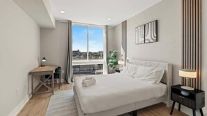 Een moderne hotelkamer met een groot bed, een bureau en uitzicht op de stad.