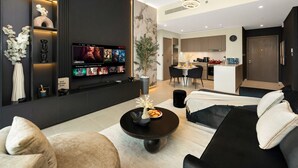 Una sala de estar moderna con un sofá negro, una mesa de centro y un televisor de pantalla plana mostrando contenido de Netflix.