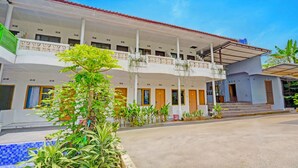 A hotel with a covered entrance, multiple balconies, and a pool area. - Collection O Subang near Ciater Subang formerly Orchid Villa Ciater (Ciater)