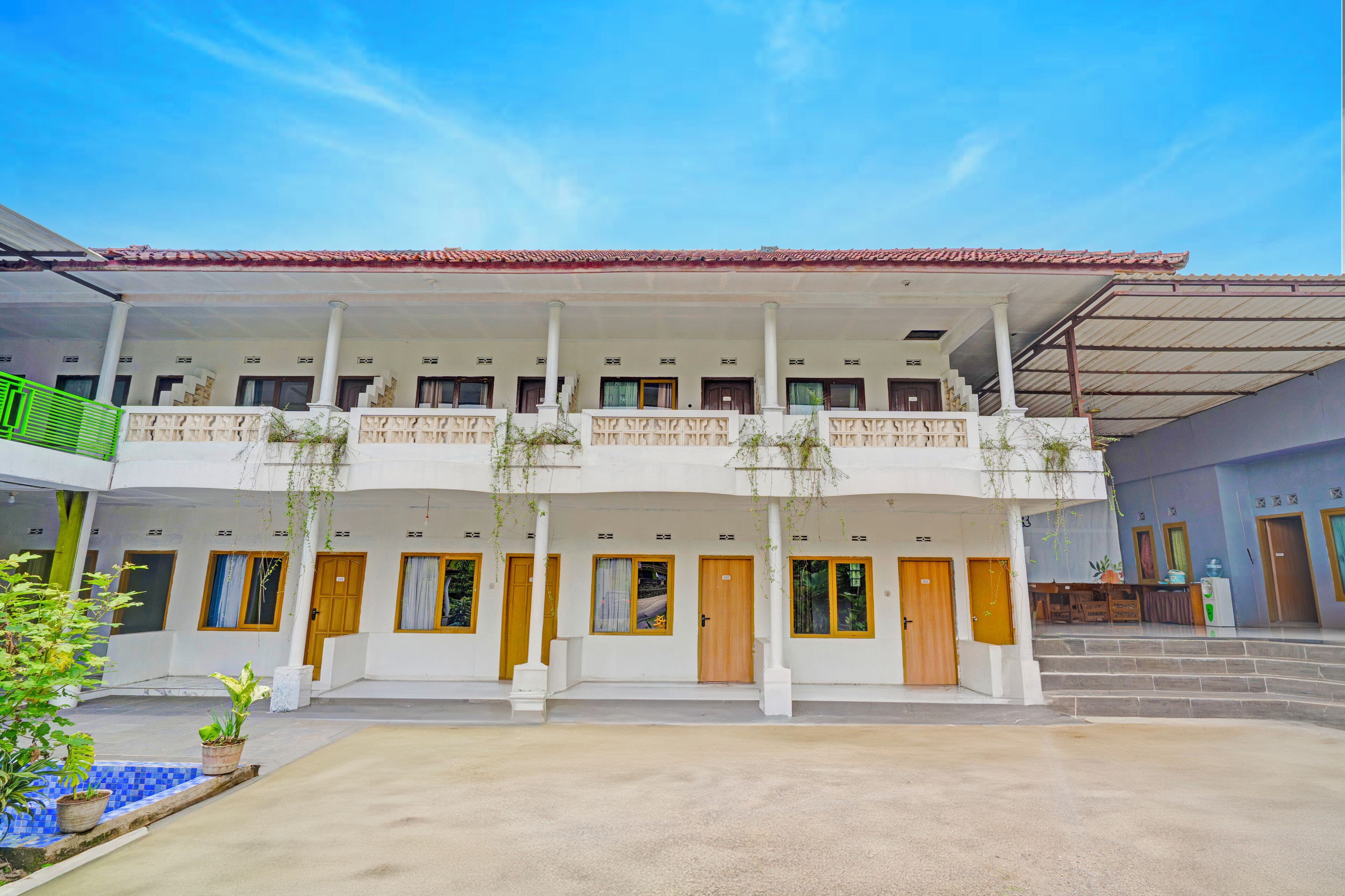 A building with multiple rooms, a covered outdoor area, and a staircase leading to an upper level.