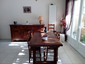A dining area with a wooden table, chairs, a lamp, and a vase with dried flowers. - Bed and Breakfast 'Automne Hiver  Été' with Shared Terrace, Private Garden and Wi-Fi (Salinelles)