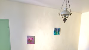 A bedroom with a wooden bed, two bedside tables, a chair, a hanging light fixture, and a wall-mounted picture. - Bed and Breakfast 'Printemps' with Shared Terrace, Private Garden and Wi-Fi (Salinelles)