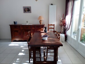 Ein Essbereich mit Holztisch, Stühlen, einer Lampe, einer Blumenvase und einem Bild an der Wand.