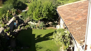 A garden with a lawn, potted plants, and a stone wall. - Bed and Breakfast 'Printemps' with Shared Terrace, Private Garden and Wi-Fi (Salinelles)