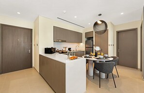 A modern kitchen with a central island, built-in appliances, and a dining area with chairs and a table.