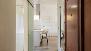 Un couloir étroit avec une porte en bois, un comptoir blanc et un tabouret.