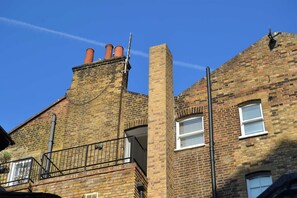 A brick building with a balcony and a chimney.