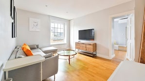 Una sala de estar moderna con un sofá, una mesa de centro, un televisor y un ventanal.