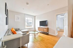 A modern living room with a sofa, a coffee table, a TV, and a window.