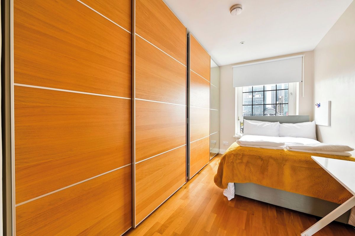 Ein modernes Schlafzimmer mit einem Bett, einem Holzschrank und einem Fenster mit Blick auf die Stadt.