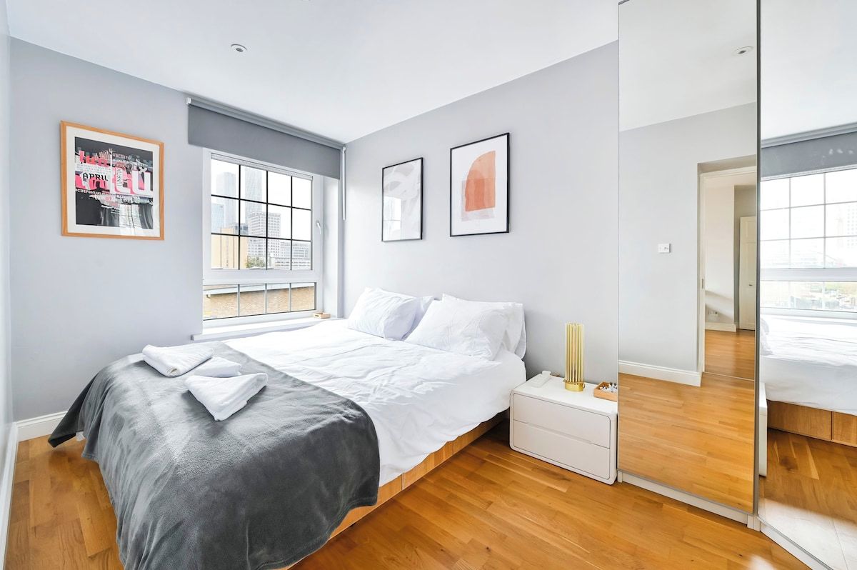 Un dormitorio moderno con cama, mesita de noche y un ventanal grande.