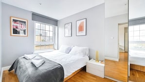 Un dormitorio moderno con cama, mesita de noche y un ventanal grande.