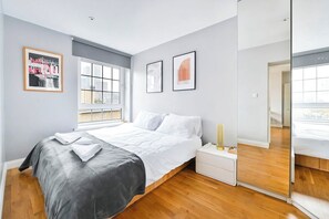 A modern bedroom with a bed, bedside table, and a large window.