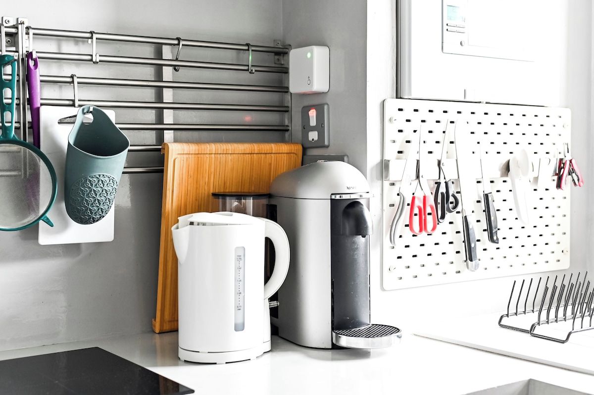Eine Küche mit Kaffeemaschine, Wasserkocher und aufgehängtem Geschirr.