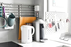 A kitchen with a coffee maker, kettle, and hanging utensils. - Canary Wharf Skyline Views (Greater London)