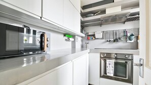 Una cocina moderna con muebles blancos, horno de acero inoxidable y microondas.