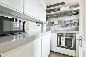 A modern kitchen with white cabinetry, a stainless steel oven, and a microwave.